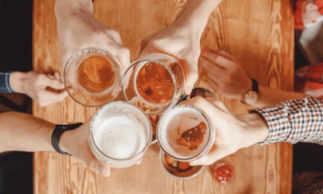 Men’s hands clink glasses of beer at a bar