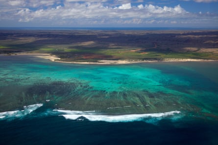 Aerial view of Ningaloo Reef, Western Australia, with turquoise water and gentle breaking waves.